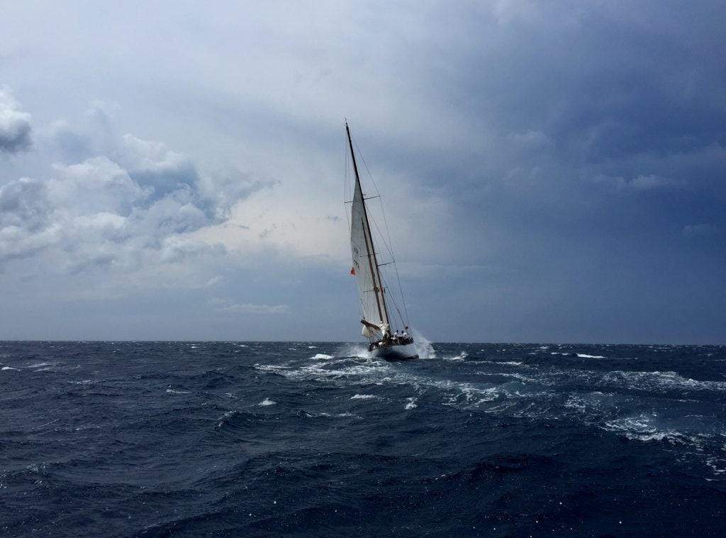A yacht sailing alone on the ocean, with stormy skies.