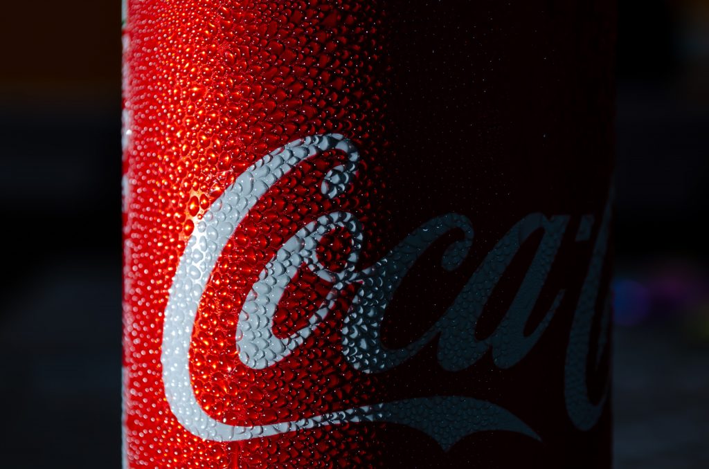 Close up of a can of coca-cola with drops of condensation on it.