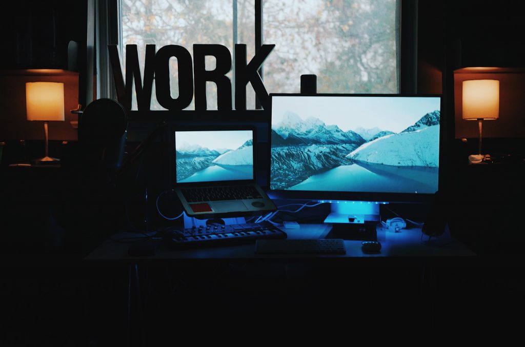 Silhouetted image of a woman sitting in front of two computer screens with the word 'Work' on the window.