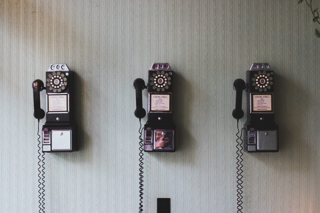 Three old-fashioned telephones hanging on a wall.