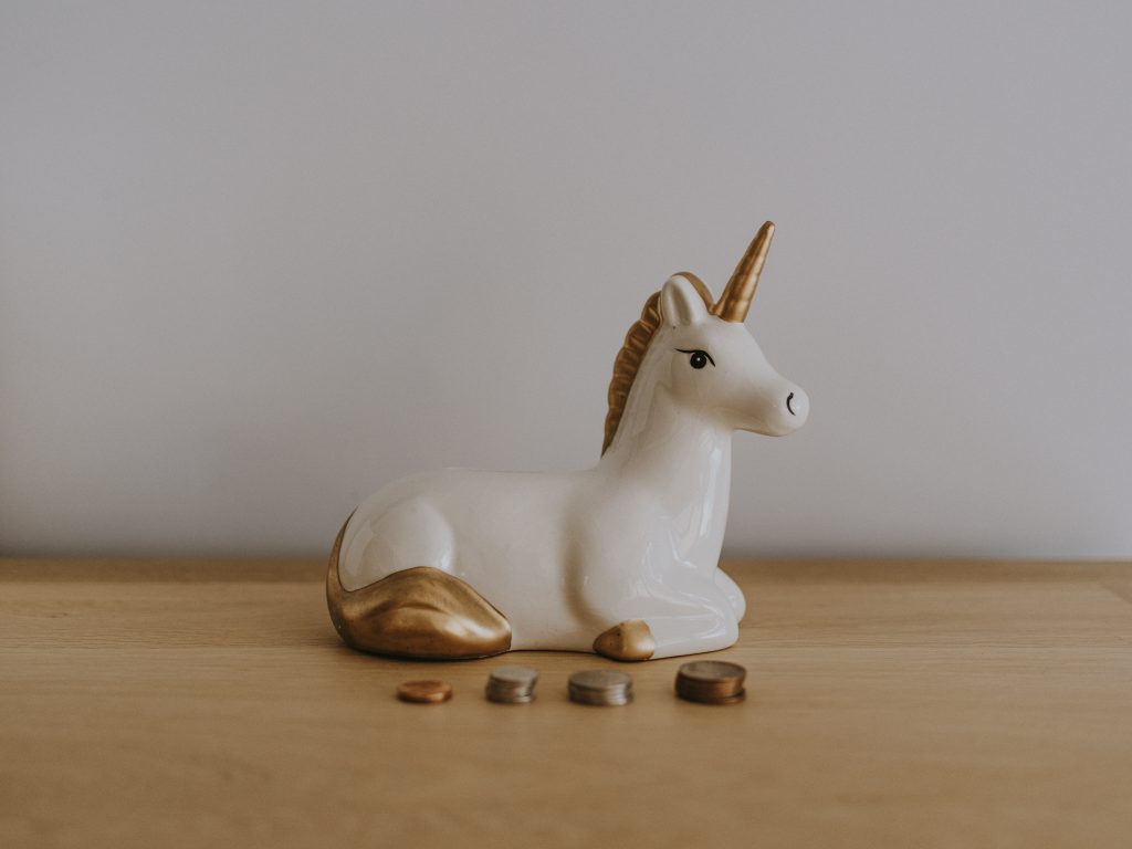 Ceramic unicorn with four rows of of coins in front of it.