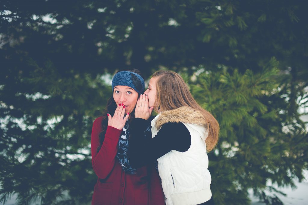 One girl whispering a secret to another.