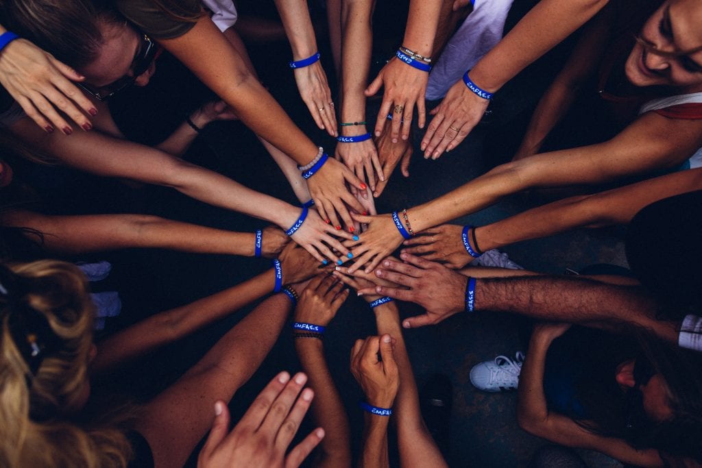 Many people in a sports team placing their hands together as one.