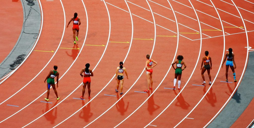 Long view of women sprinters lined up on an athletics track.