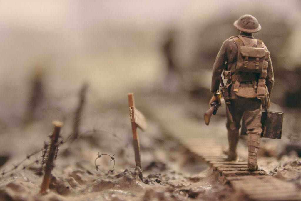 Shallow focus image of a model British toy soldier in World War 2, walking along trenchlines.