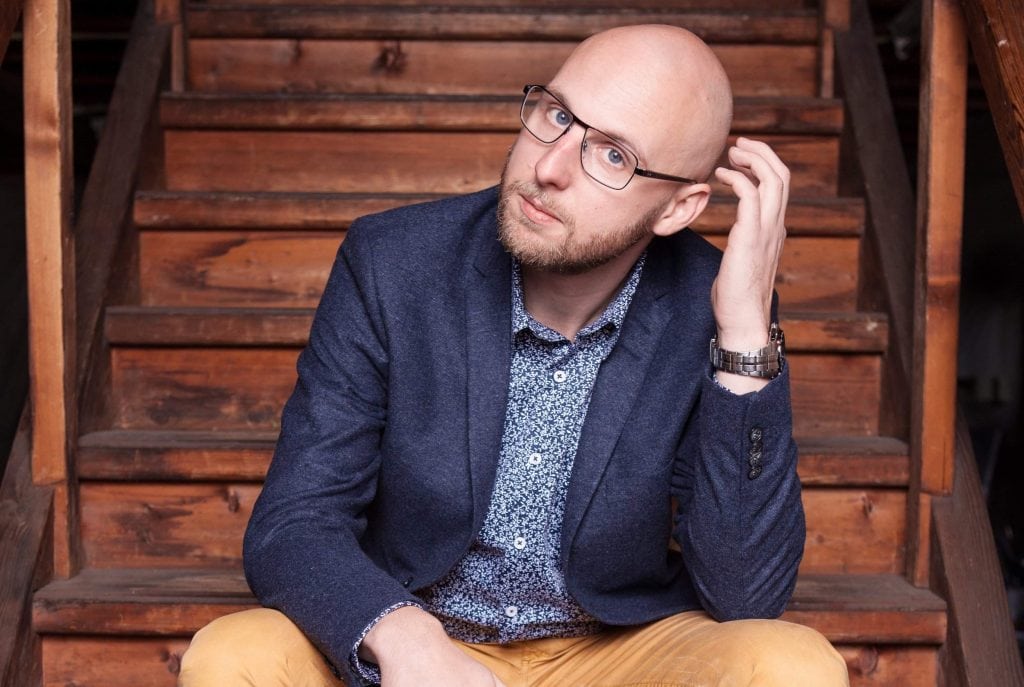 Author Jurriaan Kamer sitting on stairs, looking at the camera.
