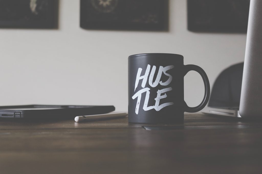 Coffee mug on table with the word 'Hustle' written on the mug