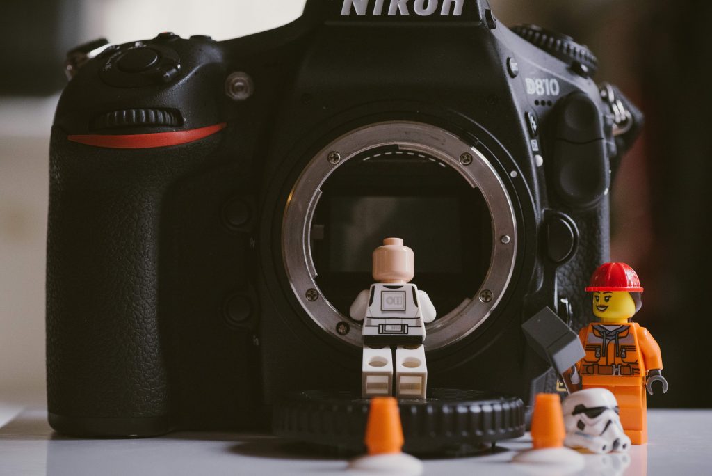 Two Lego figures inspecting a digital camera.