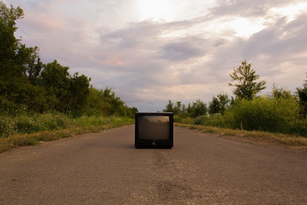 Television set lying in the middle of an empty road.
