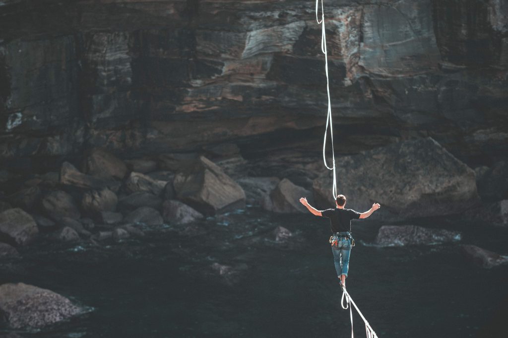 Man walking a tightrope over a canyon.
