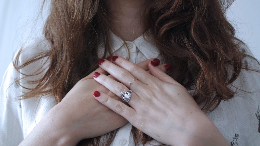 Close-up of woman holding her hands to her chest.