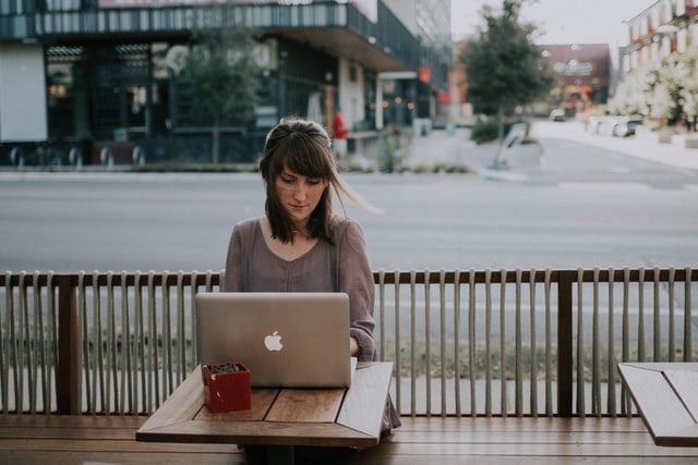 Young woman working outside on a laptop at a coffee shop.