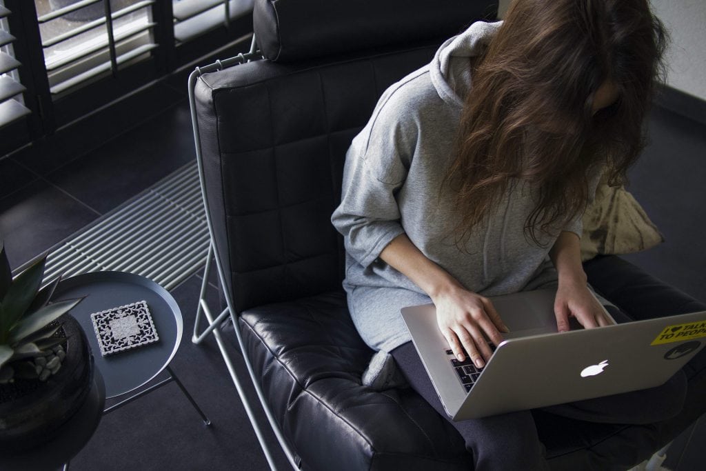 Woman sitting on a comfortable chair, working on a laptop.