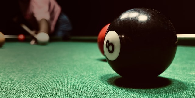 Close up of an 8 ball on a green billiard table.