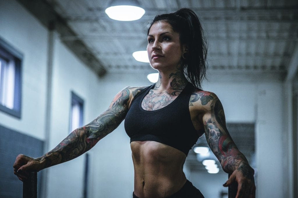 Fit, tattooed woman in black sports bra.