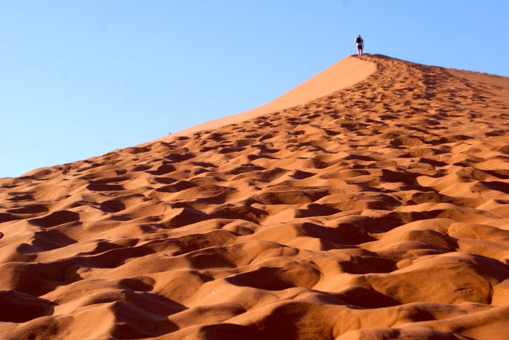 Man in the far distance at the top of a sand dune.