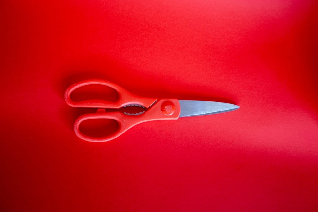 Red scissors on a red background.