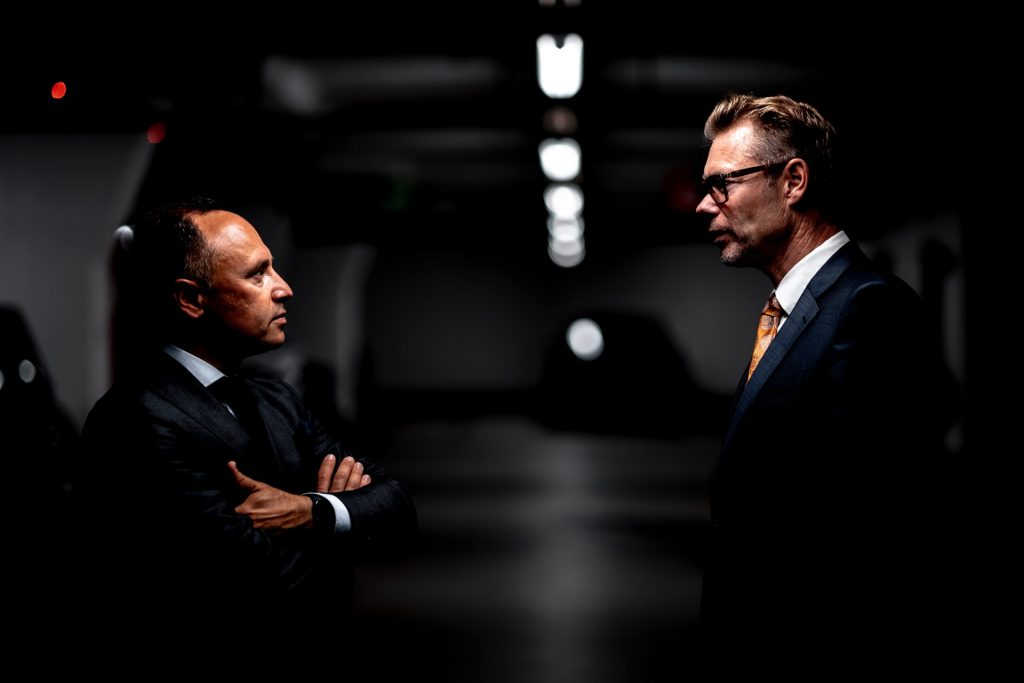 Two men in suits conversing in a tunnel.