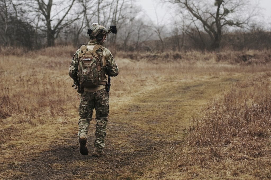 Soldier in camouflage walking in forest.