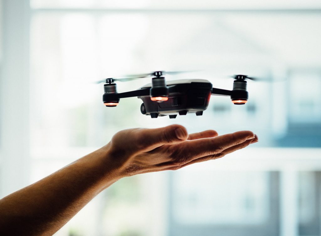 Small drone hovering over a human hand.