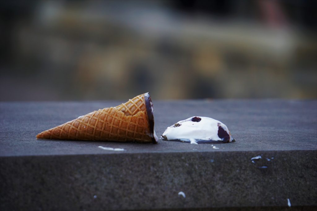 Ice-cream and cone that's been dropped on the sidewalk.