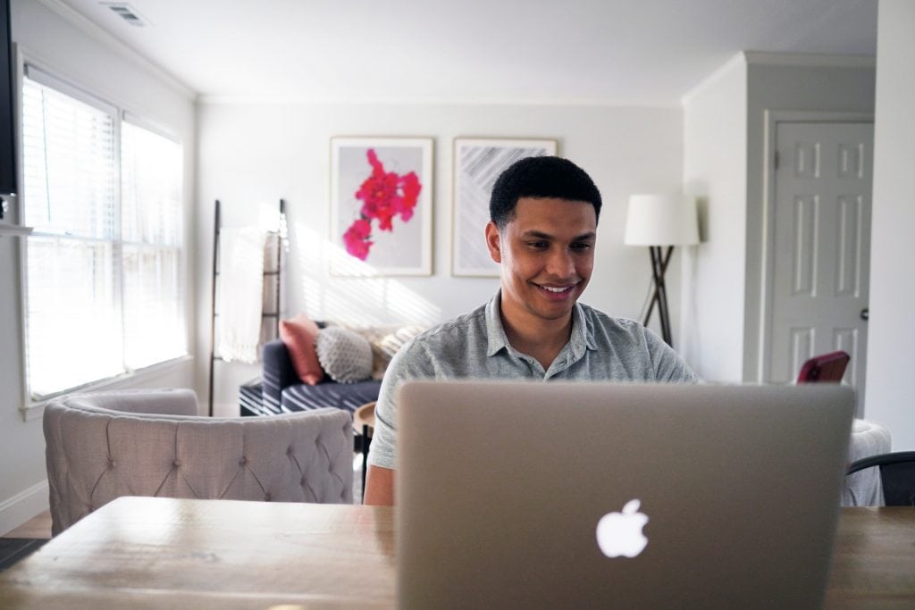 Smiling man using laptop in lounge.