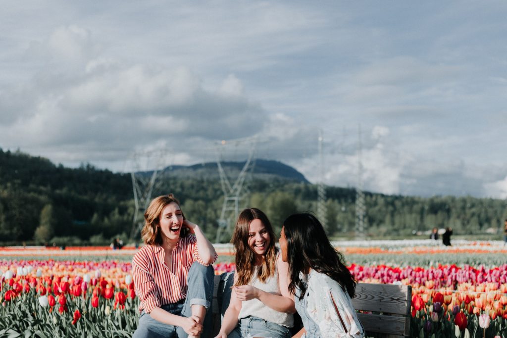 Three young women enjoying each other's company on a bench.