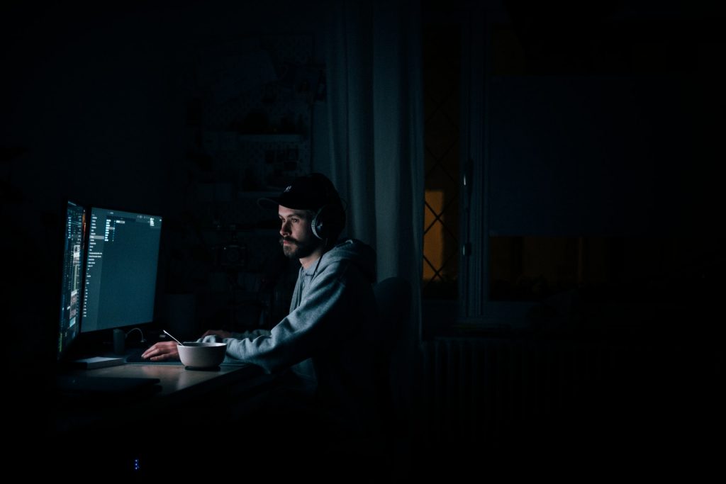 Man working at computer in darkness.