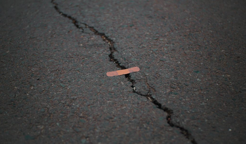 Band-aid placed across crack in road surface.