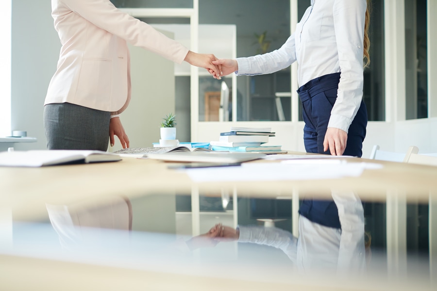 Handshake of two businesswomen over workplace