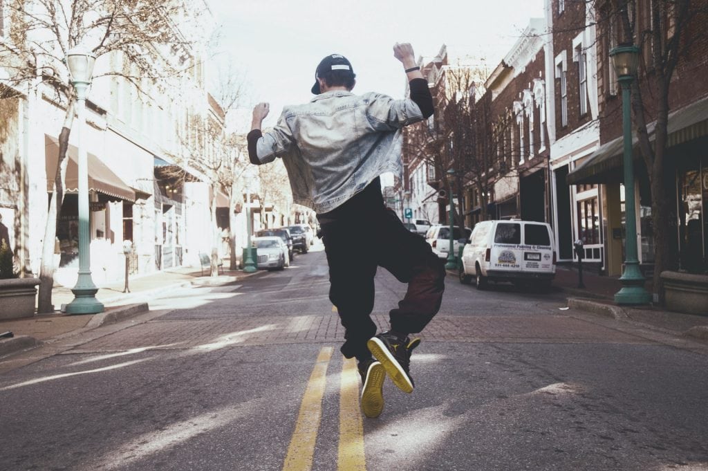 man jumping in celebration in the middle of a quiet street