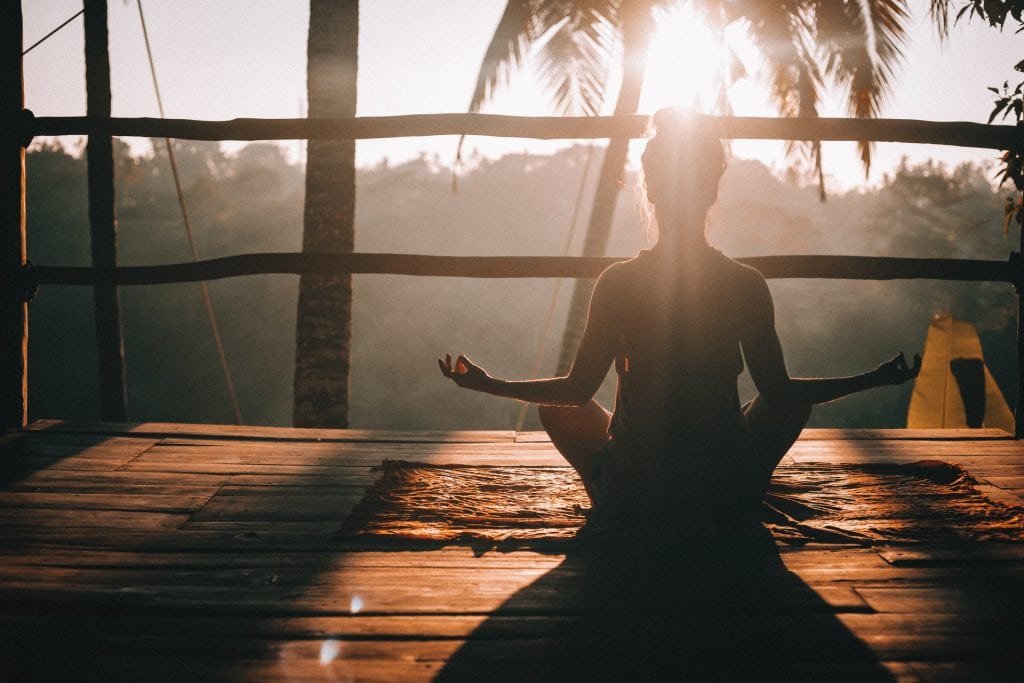 woman performing yoga pose at sunset
