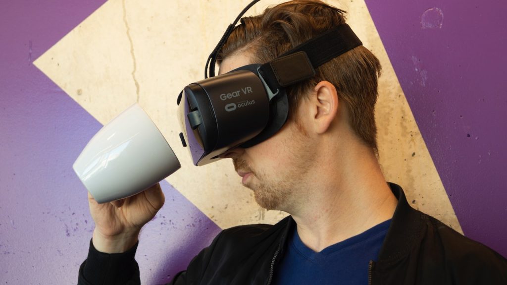 man in VR headset looking at empty coffee mug